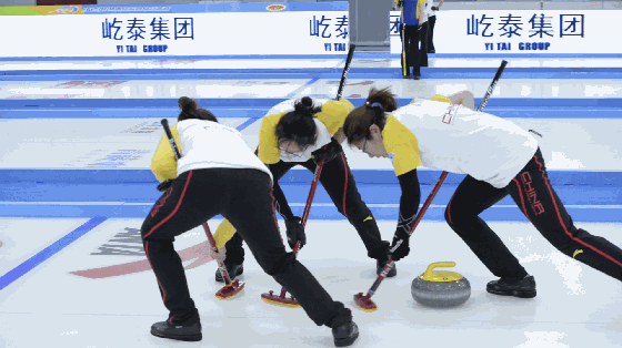 中国女子冰壶队队员们正在全力擦冰.